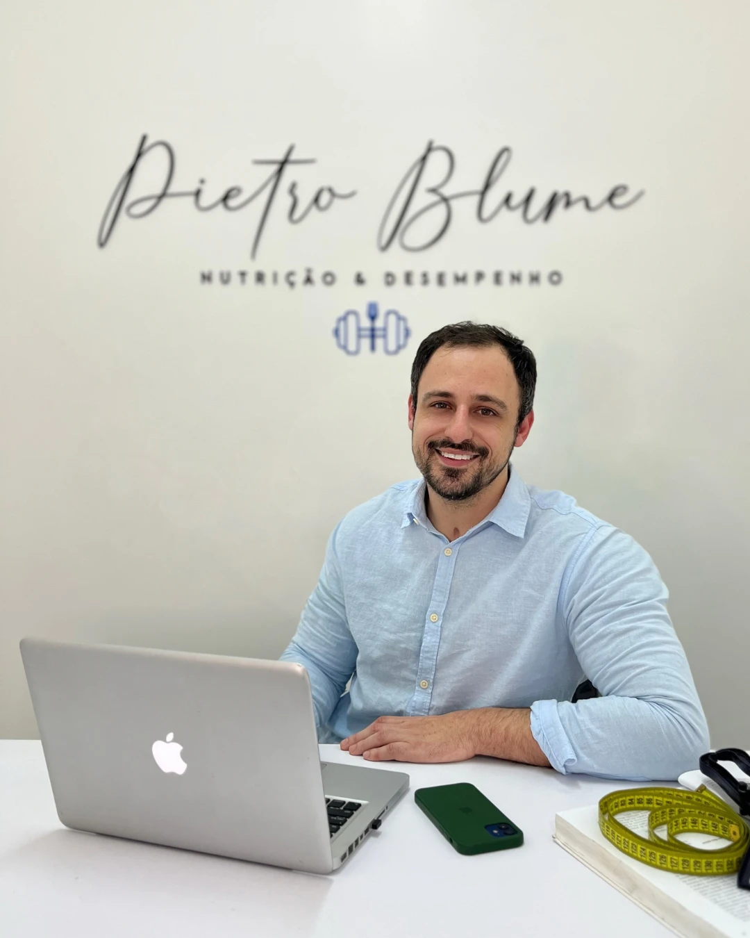Pietro Blume sorrindo, sentado à mesa do consultório